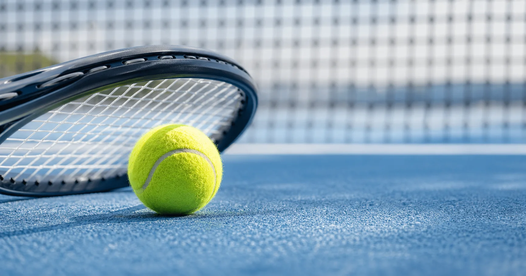 Tennisball und Schläger auf einem Hartplatz als Einstieg in Tennis Sportwetten für Anfänger