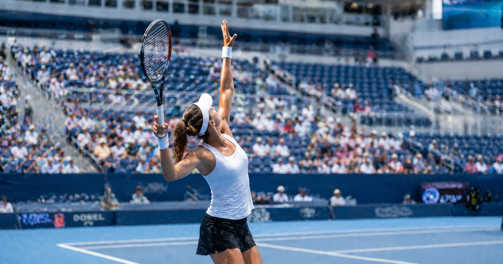 Tennisspielerin beim Aufschlag auf einem Hartplatz bei einem WTA-Turnier